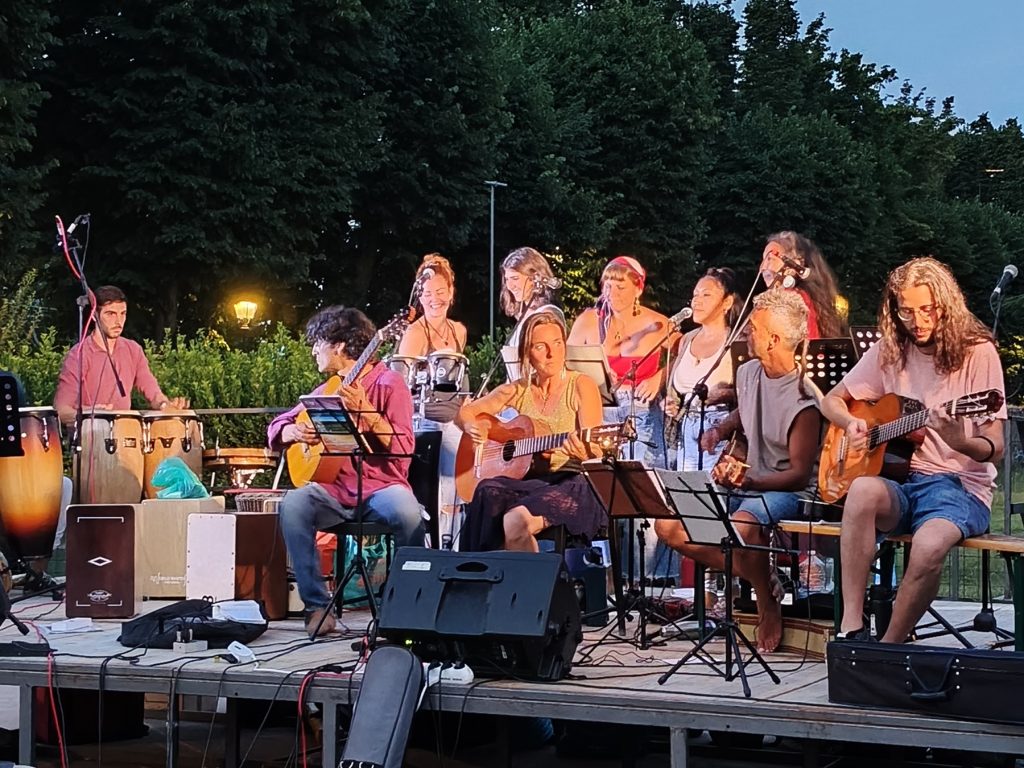 L'ensemble del Colectivo su un palco all'aperto all'imbrunire: chitarre, voci, congas e cajón