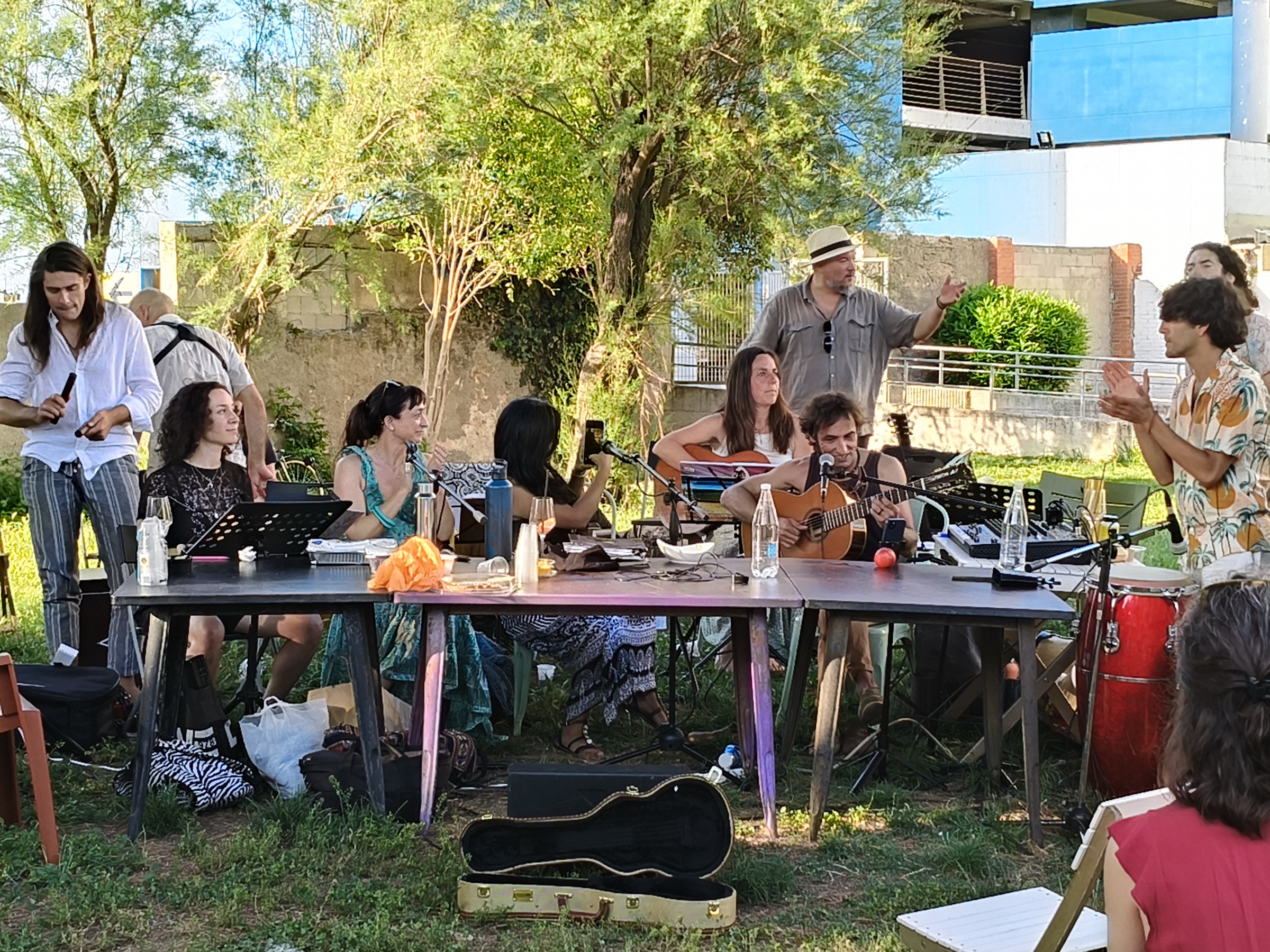Il Colectivo prova all'aperto attorno a due tavoli, con leggii, chitarre e percussioni