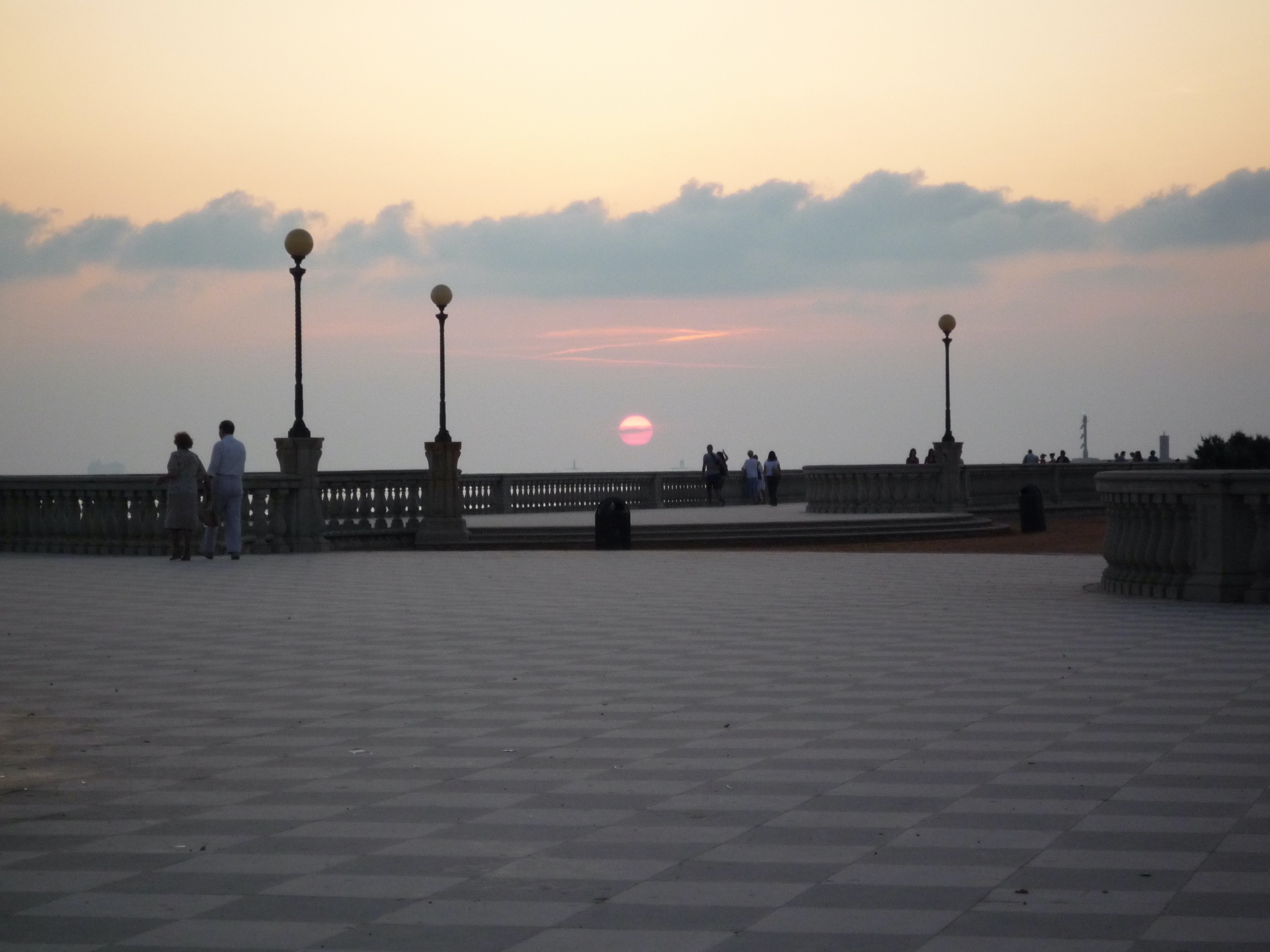 La Terrazza Mascagni di Livorno al tramonto, i lampioni in fila e il sole basso sul mare